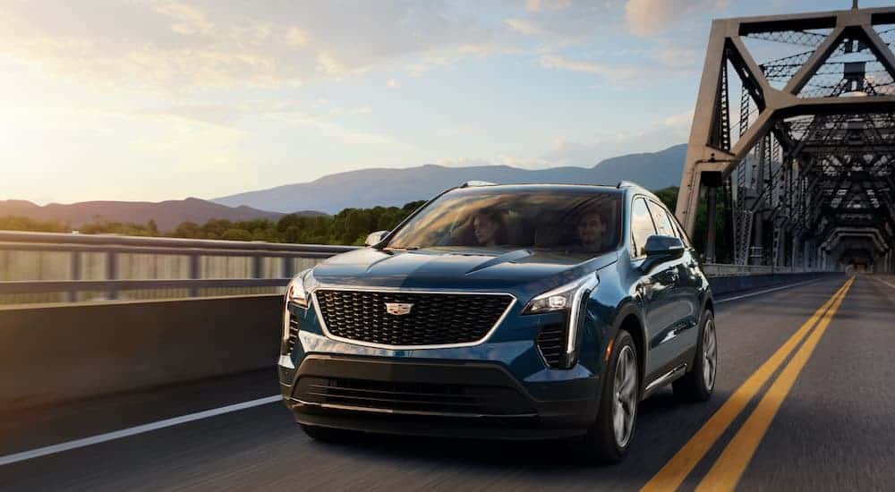 A blue 2019 used Cadillac XT4 is driving over a bridge.