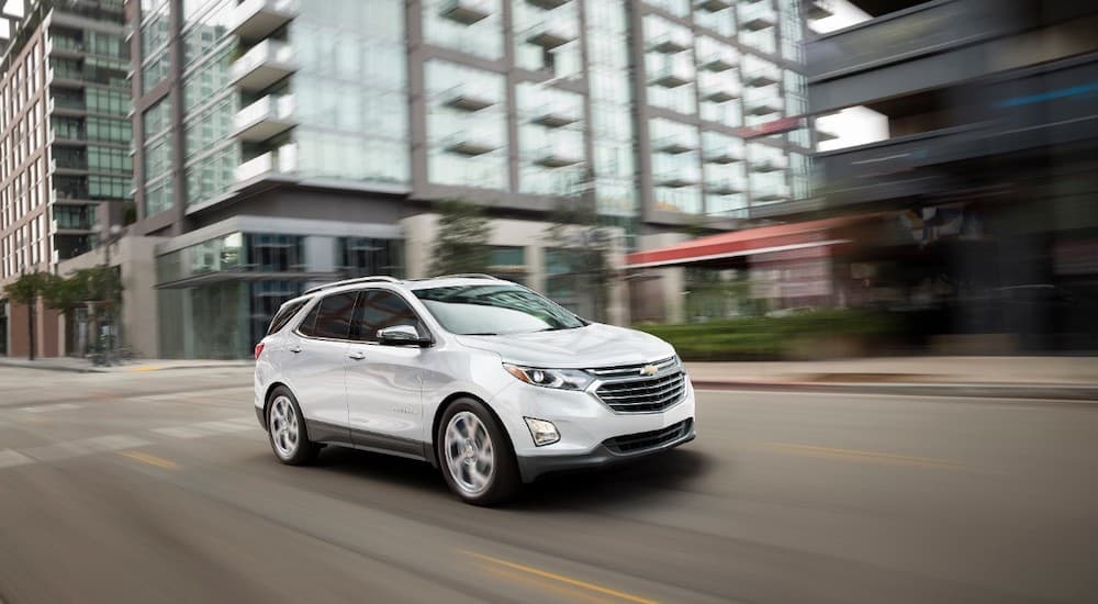A white 2018 Used Chevy Equinox is driving on a city street.