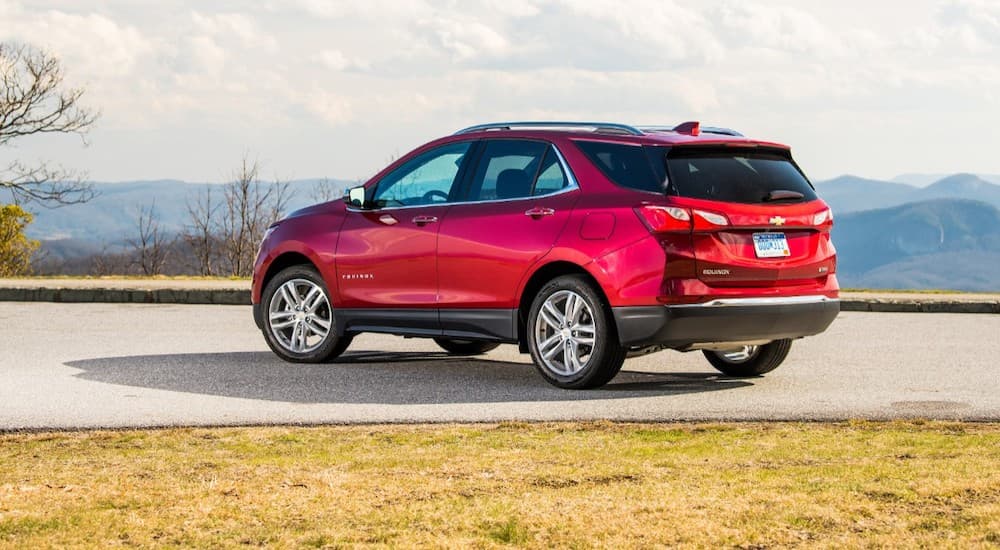 A red 2020 Used Chevy Equinox is shown from the rear in front of distant mountains.