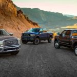 A brown, a blue, and a black 2019 used Ram 2500 are parked on a mountain road in the desert.