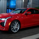 A red 2021 Cadillac CT4 is driving on a city street at night.