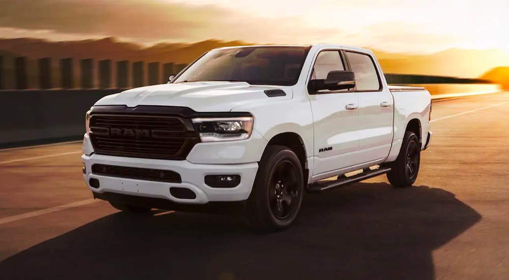A white 2021 Ram 1500 diesel is on a track at sunset.