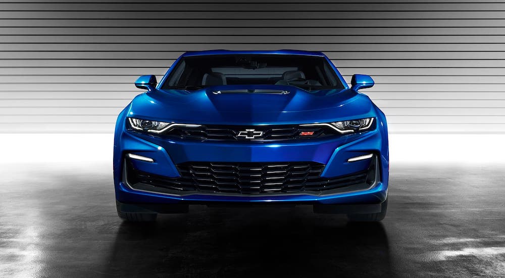 A blue 2021 Chevy Camaro SS is shown from the front parked in front of a garage door.