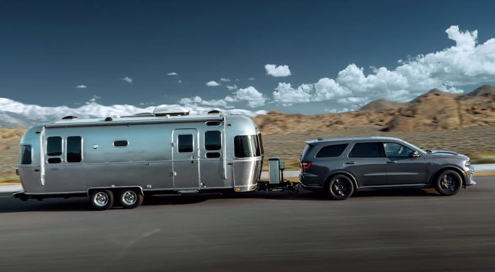 A grey 2021 Dodge Durango is shown towing an Airstream from the side on a desert road.