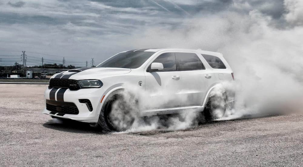 A white 2021 Dodge Durango is doing a burn out in a parking lot.