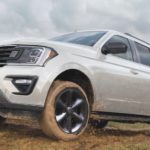 A white 2021 Ford Expedition is driving on a dirt road.