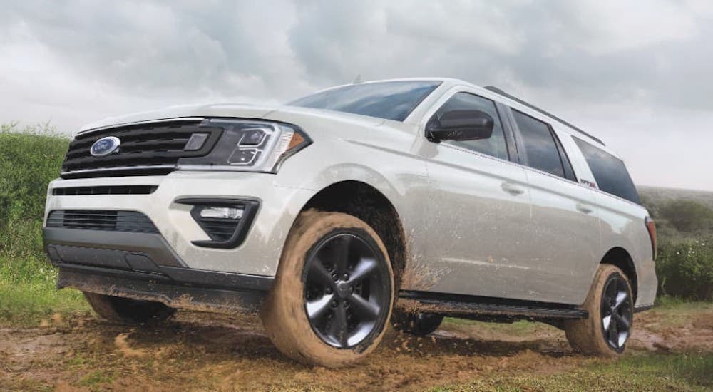 A white 2021 Ford Expedition is driving on a dirt road.