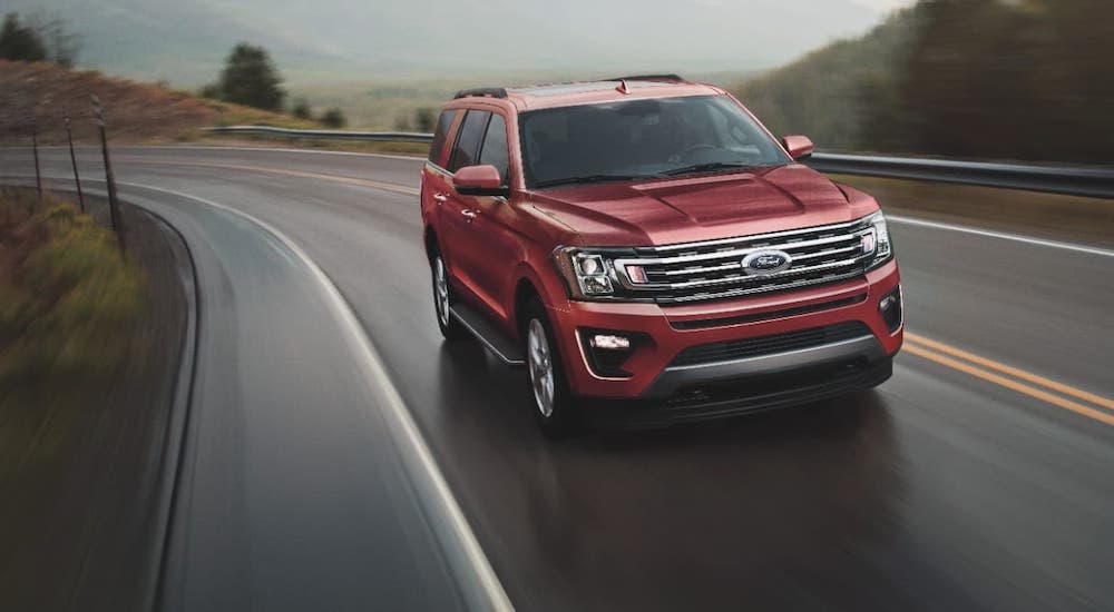 A red 2021 Ford Expedition is driving on a wet highway after winning the 2021 Ford Expedition vs 2021 Chevy Tahoe comparison.