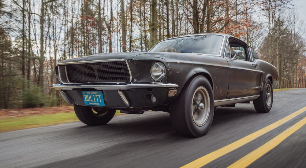 A green 1968 Ford Mustang Bullitt is shown driving down the road after looking at a brand new 2021 Ford F-150.