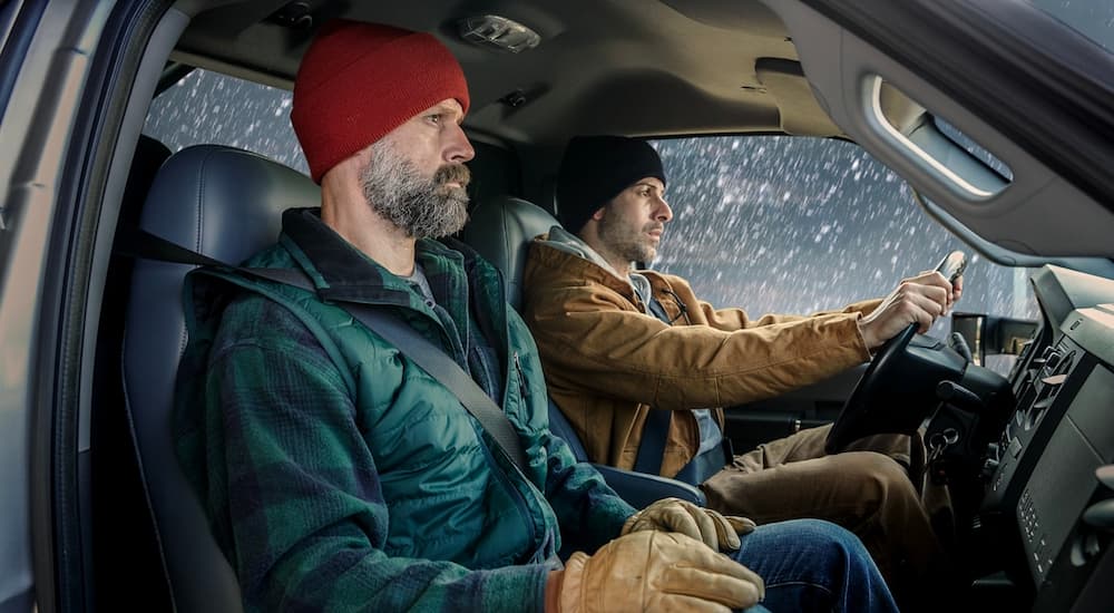 Two men are shown inside a 2021 Ford F-750 driving through the snow.