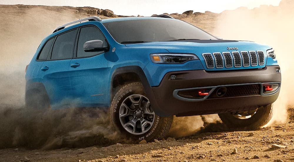 A blue 2021 Jeep Cherokee is off-roading in dirt.