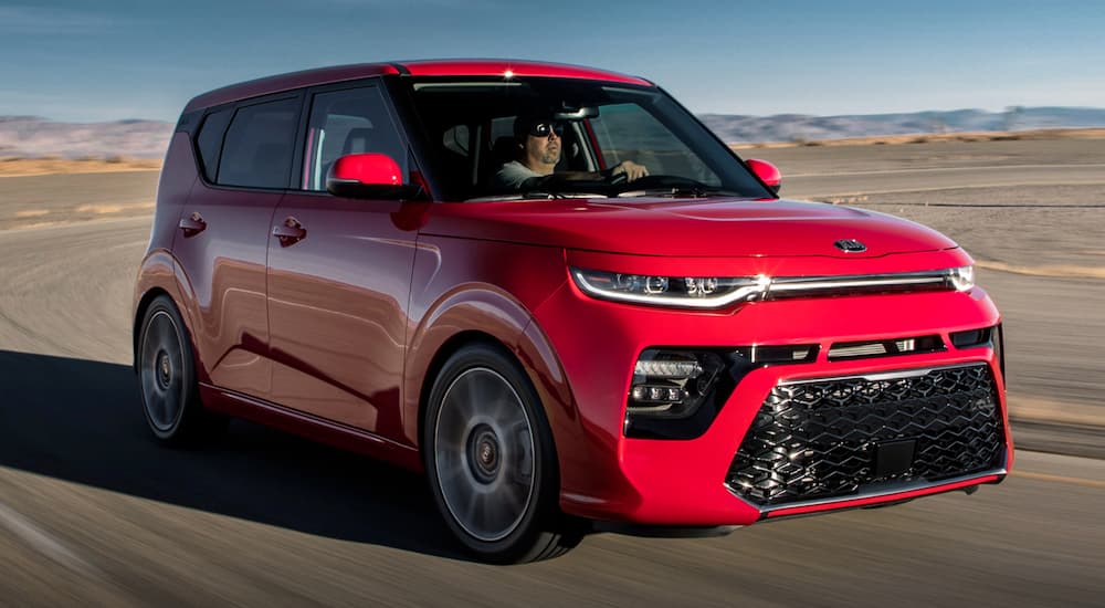 A red 2021 Kia Soul Turbo is driving on a desert road.