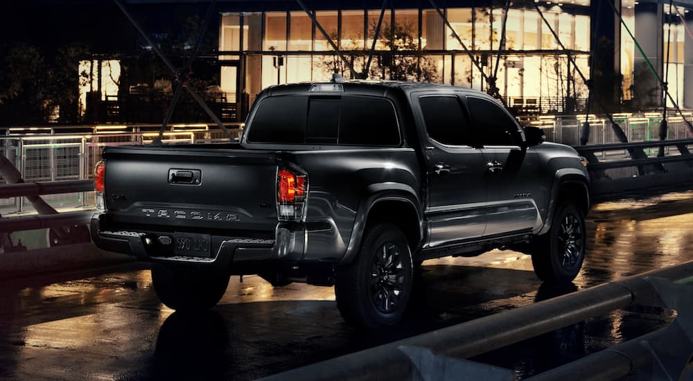 A black 2021 Toyota Tacoma Nightshade is parked on a city street at night.