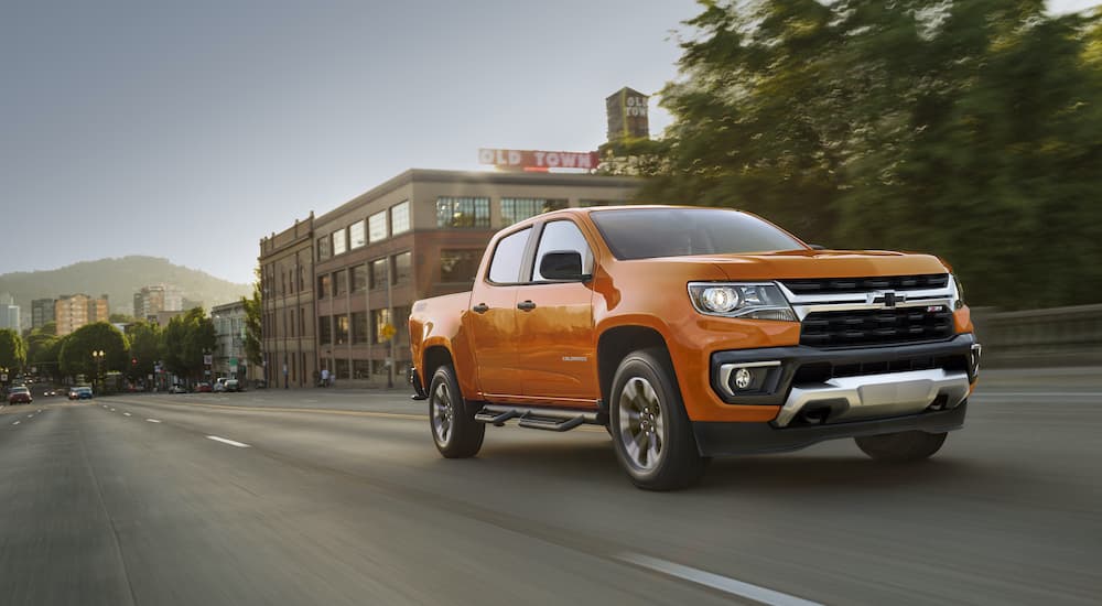 An orange 2021 Chevy Colorado Z71 is shown from the front driving on an open road.
