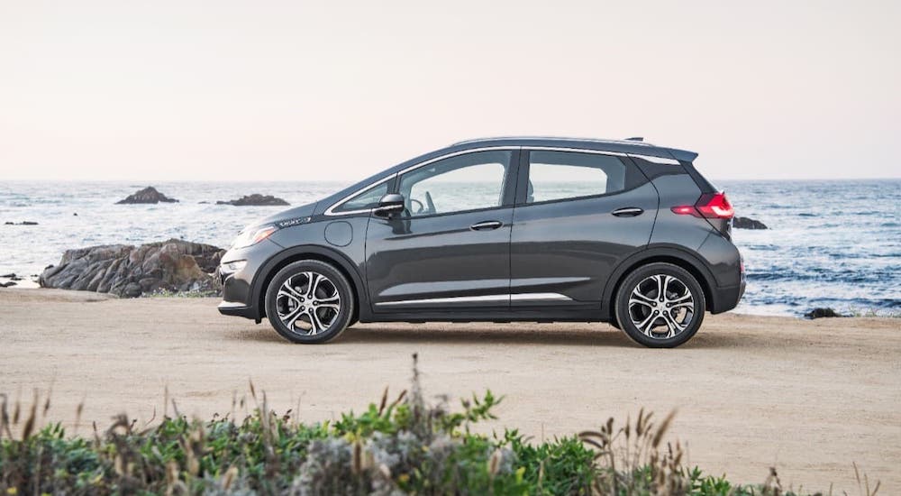 A black 2021 Chevy Bolt EV is shown from the side while parked on a beach.