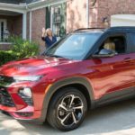 A mother is waving at a teen driving a red 2021 Chevy Trailblazer.