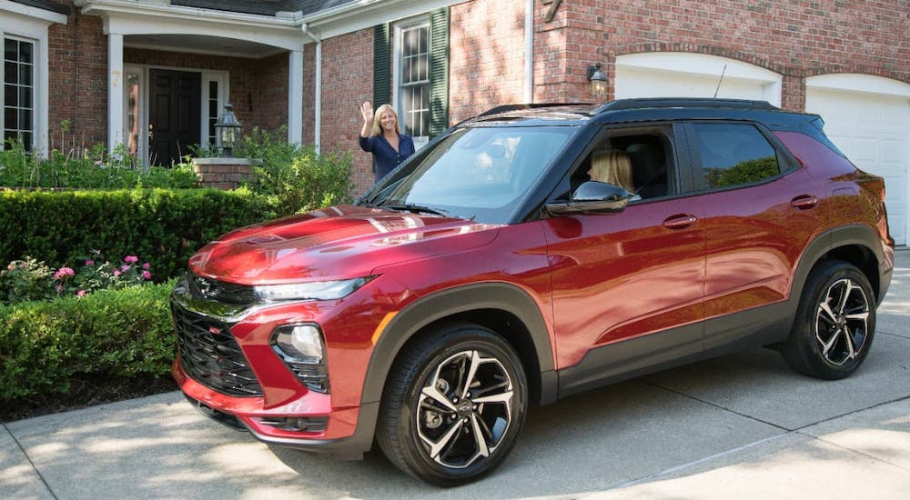 A mother is waving at a teen driving a red 2021 Chevy Trailblazer.