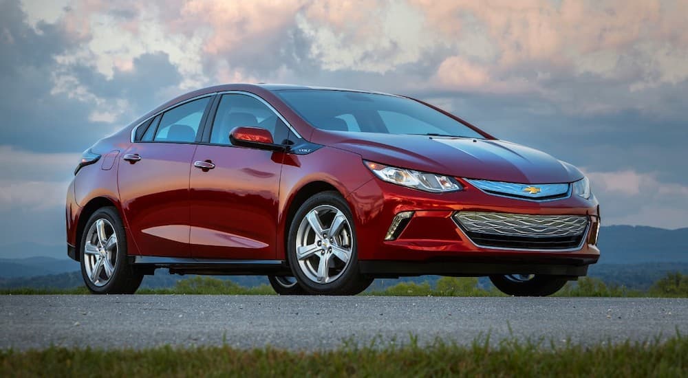 A red 2019 Chevy Volt is parked in front of colorful clouds.