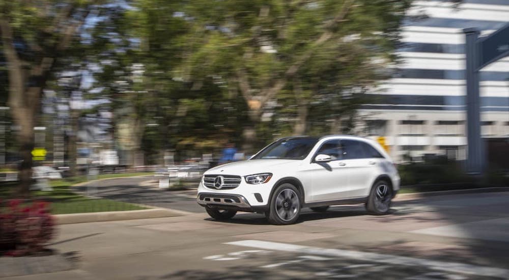 A white 2021 Mercedes-Benz GLC SUV 300 is rounding a corner on a city street.