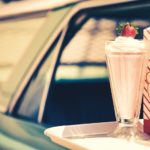 A milkshake and a bag of popcorn are sitting on a tray on a car at a drive-in theater after leaving a used car dealer in Louisville.