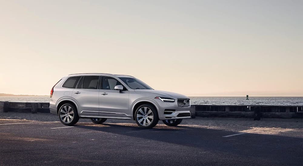 A silver 2021 Volvo XC90 is parked at a beach at dusk.