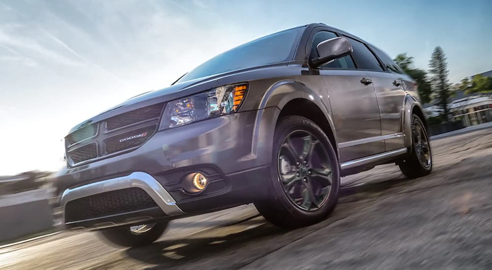 A grey 2020 Dodge Journey is shown from a low angle driving on a city street.