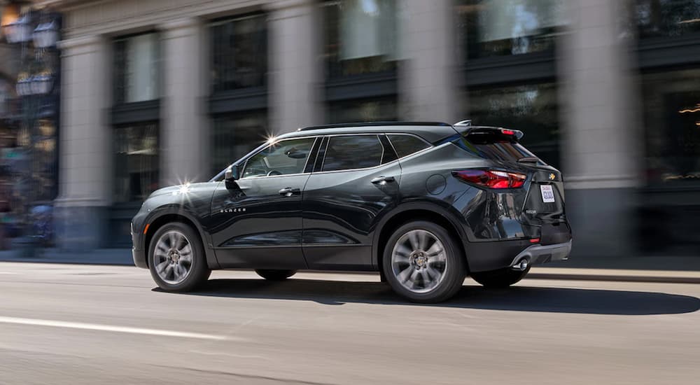 A dark grey 2021 Chevy Blazer is driving on a city street.