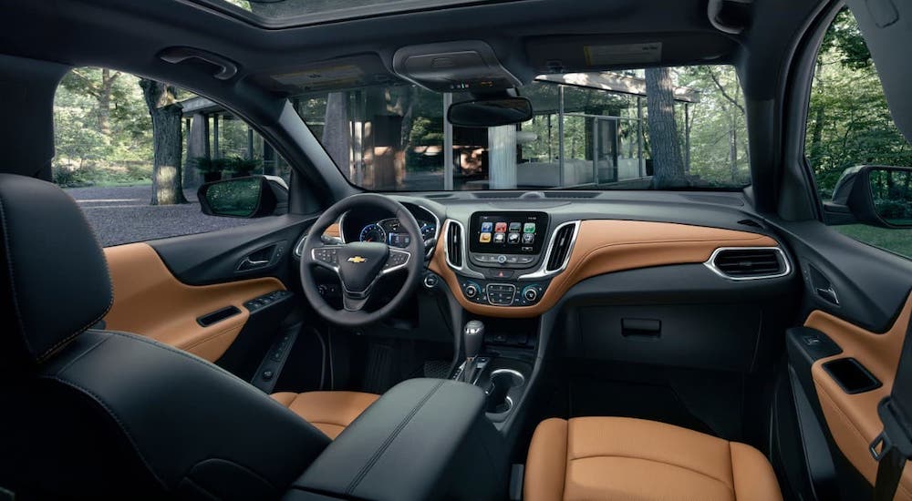 The tan and black interior of a 2021 Chevy Equinox is shown from the passenger's seat.