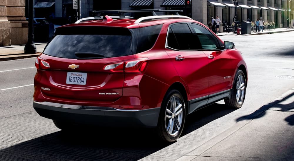 A red 2021 Chevy Equinox is shown from the rear on a city street.