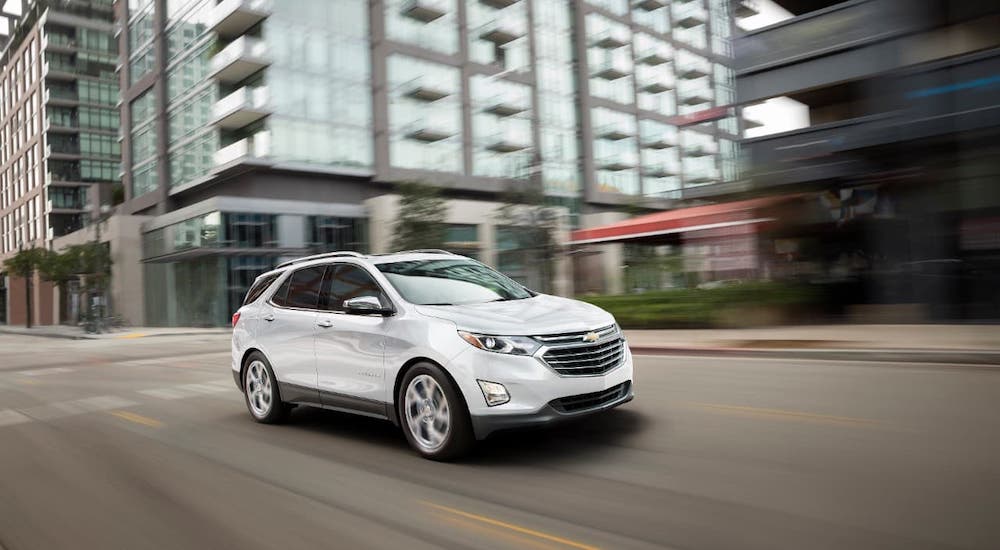 A white 2021 Chevy Equinox is driving in a city.