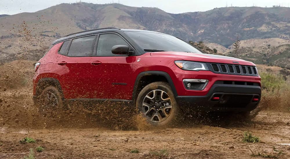 A red 2021 Jeep Compass is off-roading in mud.