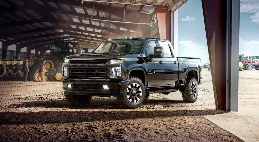A black 2021 Chevy Silverado HD Carhartt Edition is parked in a barn with machinery.
