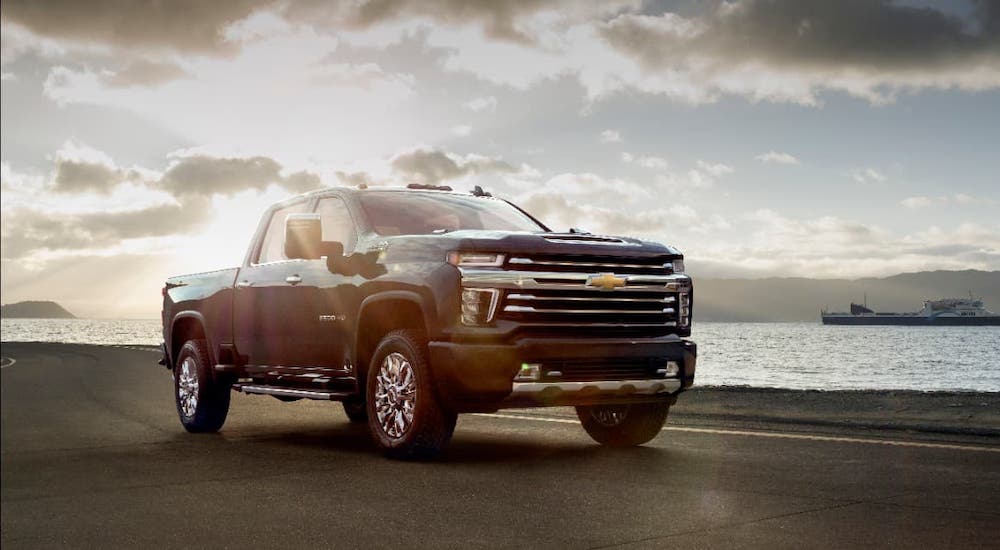 A gray 2021 Chevy Silverado HD High Country is driving along a body of water.