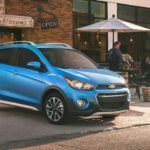 A blue 2021 Chevy Spark is parked in front of a cafe.