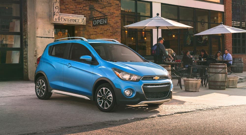 A blue 2021 Chevy Spark is parked in front of a cafe.