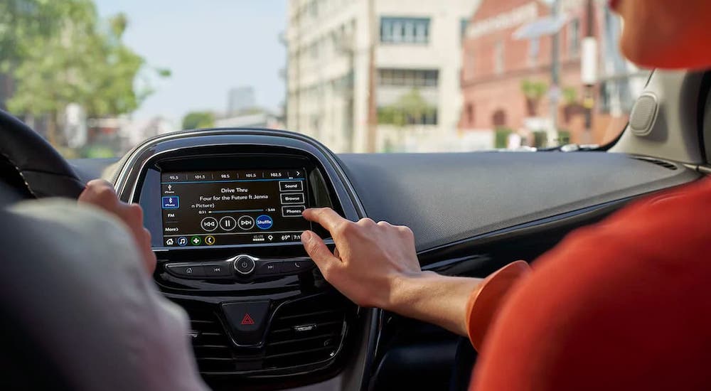Passengers in a 2021 Chevy Spark are using the infotainment screen while driving.