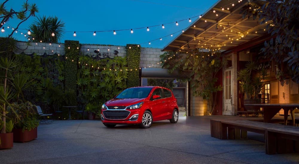 A red 2021 Chevy Spark is parked under lights at night.