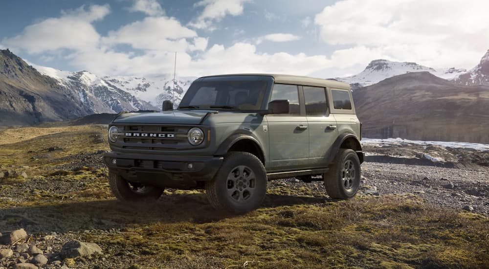 A green 2021 Ford Bronco 4 door is parked off-road in front of distant mountains.