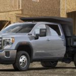 A grey 2021 Chevy 3500 Chassis Cab is parked in front of a house under construction.