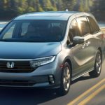 A silver 2021 Honda Odyssey is driving past a pond after winning the 2021 Honda Odyssey vs 2021 Toyota Sienna comparison.