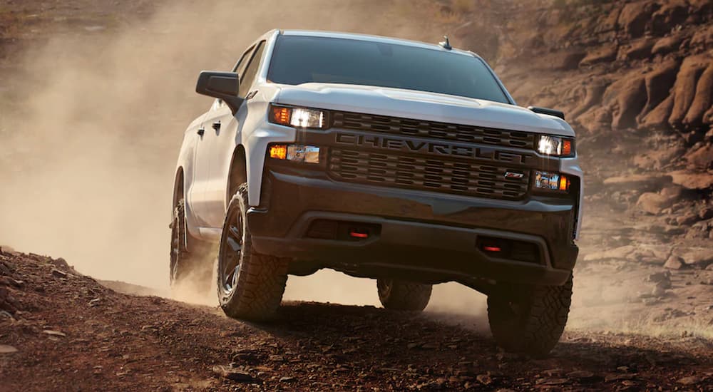 A white 2021 Chevy Silverado 1500 is kicking up dirt while on a trail.
