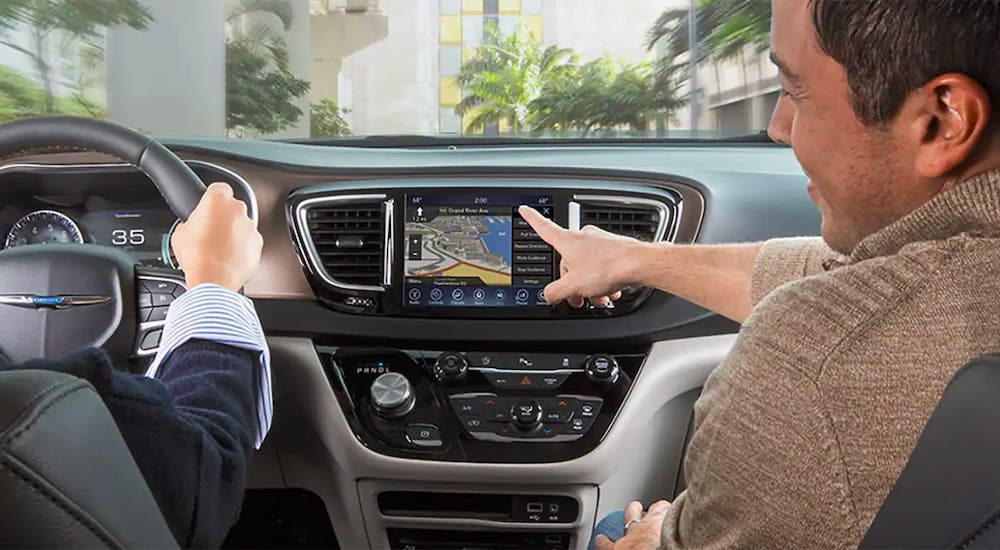 A passenger is pointing to the infotainment screen inside a Chrysler vehicle after leaving a Chrysler dealership.