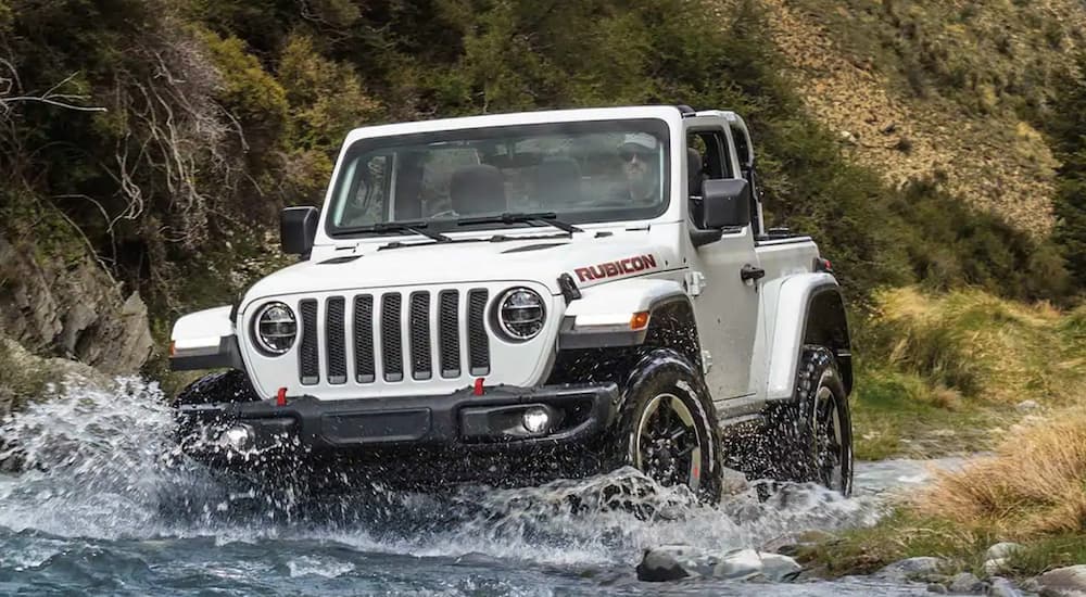 A white 2021 Jeep Wrangler Rubicon is crossing a river.