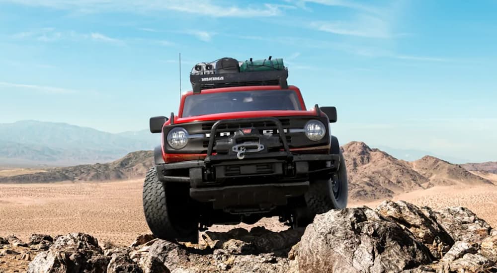 A red 2021 Ford Bronco is shown from the front parked on rocks in the desert.