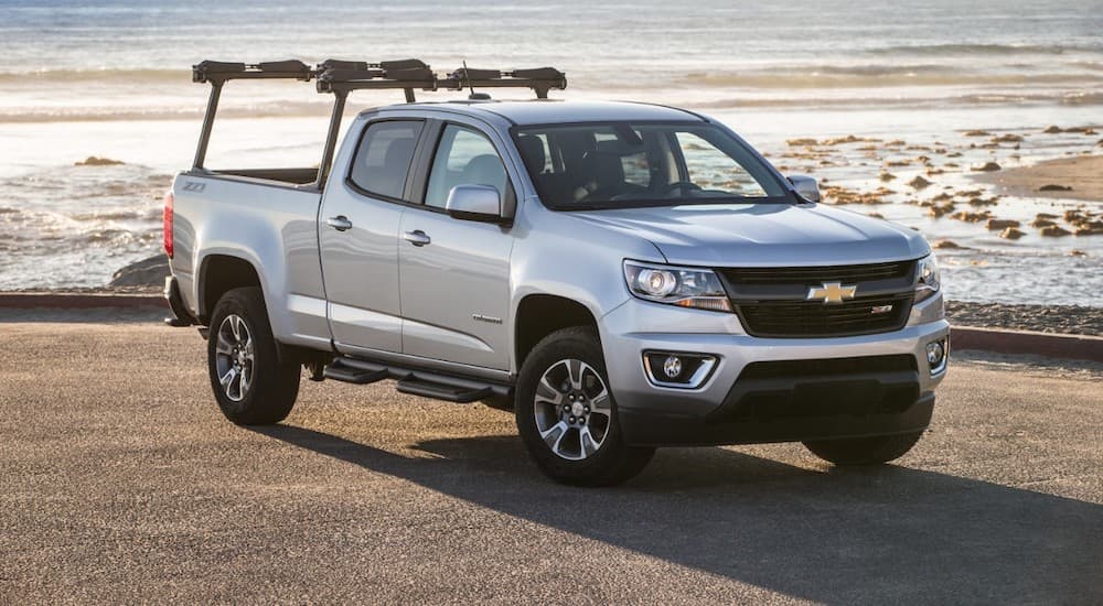 A white 2015 Chevy Colorado, a popular pre-owned Chevy truck, is parked in front of the ocean.