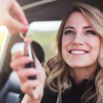 A close up shows a smiling woman being handed a set of car keys.
