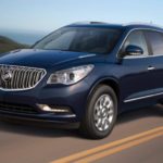 A blue 2017 used Buick Enclave is driving uphill past the ocean.