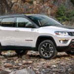 A white 2020 used Jeep Compass is parked on a rocky river bank.