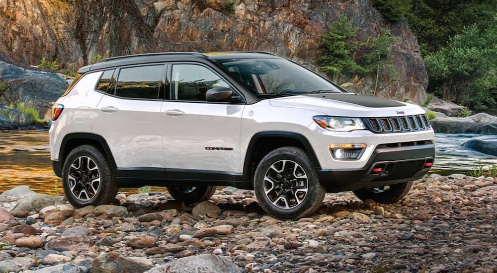 A white 2020 used Jeep Compass is parked on a rocky river bank.
