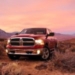 A red 2020 Ram 1500 Classic is parked in a desert at dusk.